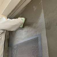 左官工事、外壁モルタル塗作業です。表面クラック防止のため、グラスファイバーネットをなじませています。美しい仕上がりは勿論のこと、一つ一つの作業をしっかり丁寧に行います。