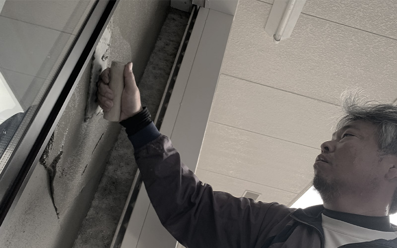 左官業務の外壁モルタル塗り作業です。鏝で塗りつけの作業をしています。